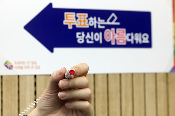 제22대 국회의원선거를 하루 앞둔 9일 오후 서울 영등포구 YDP미래평생학습관에 마련된 투표소에서 관계자가 기표용구를 들어보이고 있다. [연합뉴스]