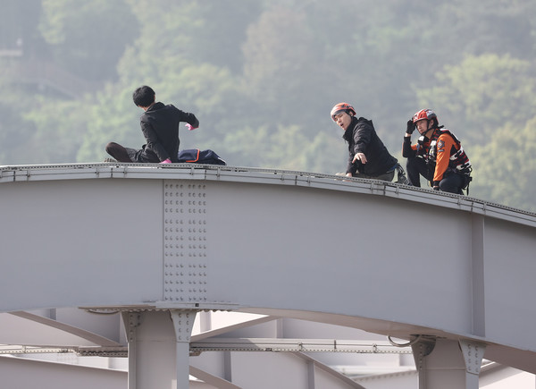 신원불명의 남성이 17일 오전 서울 용산구 한강대교 아치 위에 올라가 있다. [연합뉴스]
