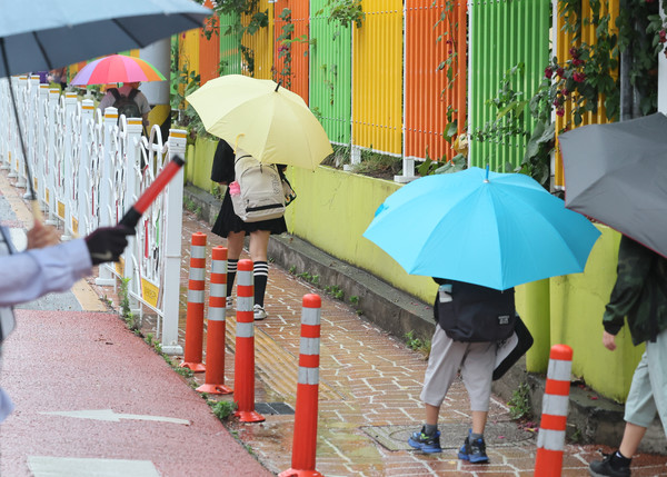 제주도에 장마가 시작된 20일 오전 제주시 노형초등학교 통학로가 우산을 든 어린이들로 붐비고 있다. [연합뉴스]