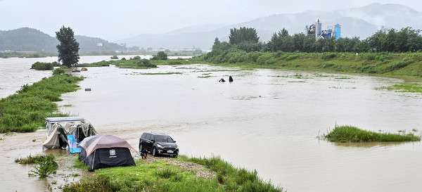 중부지방을 중심으로 많은 비가 내린 18일 물에 잠긴 섬강 문막교 인근 둔치에서 한 주민이 텐트를 철거하고 있다. [연합뉴스]