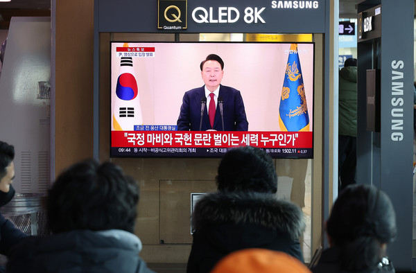 12일 오전 서울역에서 시민들이 윤석열 대통령 담화를 TV로 보고 있다. [연합뉴스]